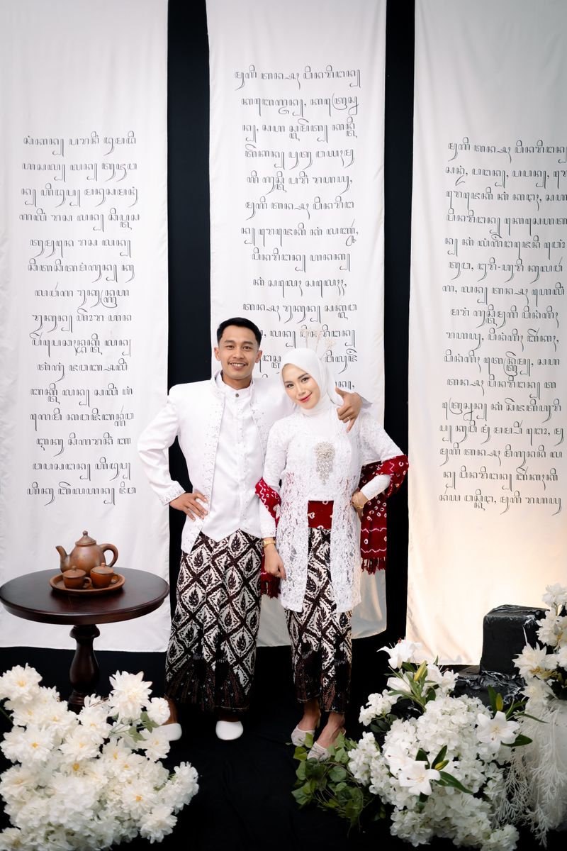 Rahardiyan dan Safrina tersenyum di depan kain beraksara Jawa