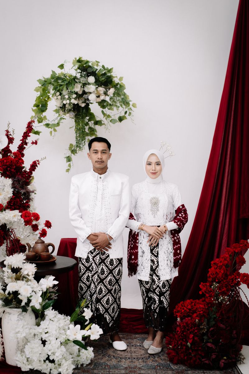 Potret pasangan mengenakan busana putih dan kain batik